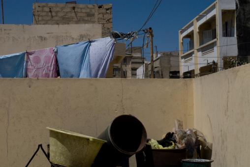 Devant le muret qui entoure le toit, des seaux et des bassines en plastique. Derrière, du linge qui sèche, des immeubles, peints ou non, et un enchevêtrement de fils électriques. Dakar, Sénégal, mars 2010.
