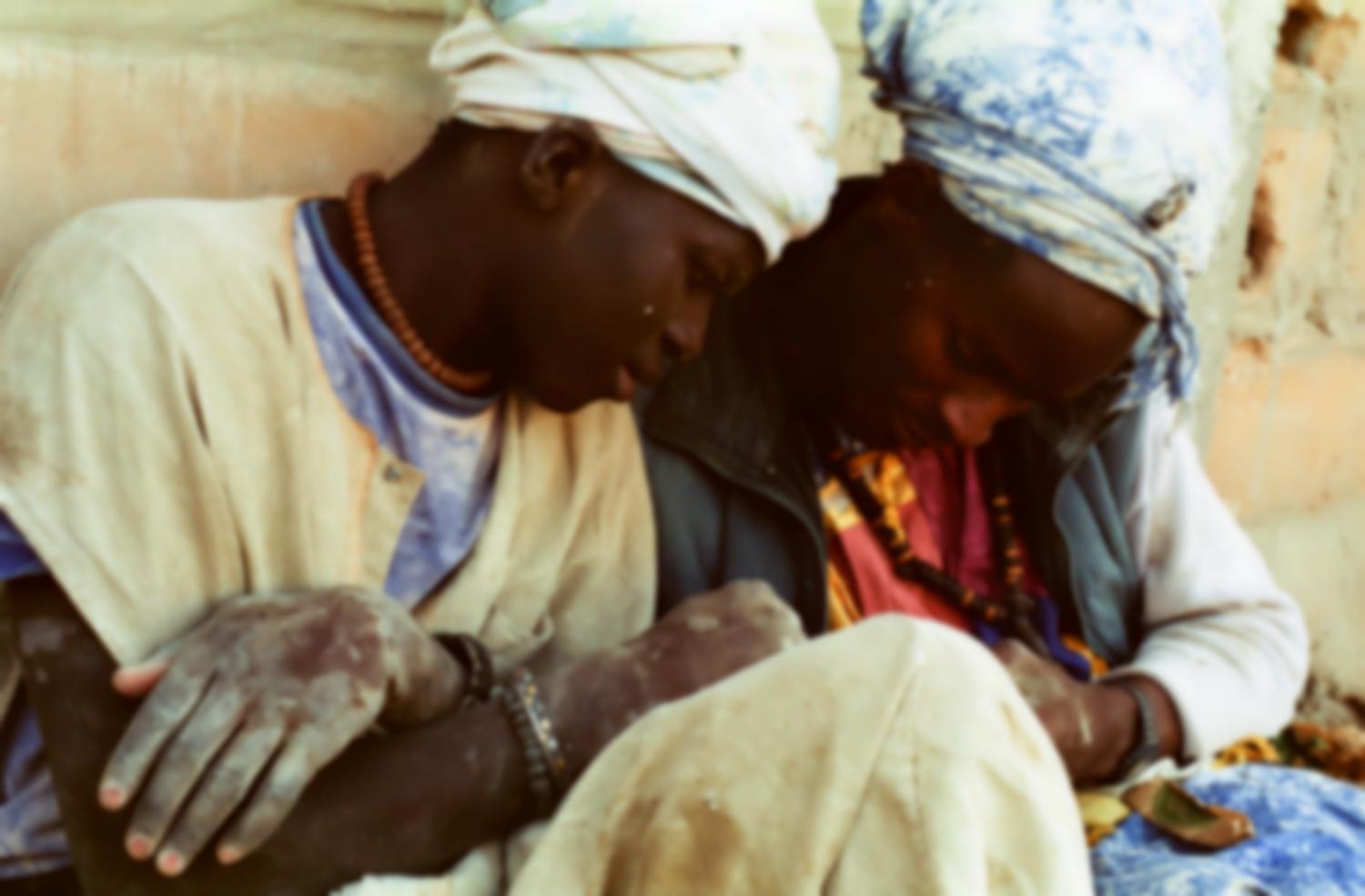 Assis contre un mur, deux Baye semblent se faire des confidences intimes. Touba, Sénégal, février 2008.