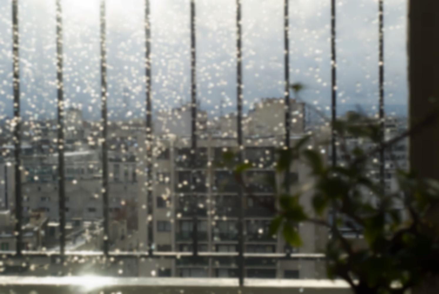 Quelques rayons de soleil passent à travers un ciel plombé et font miroiter des gouttes de pluie sur la vitre. Paris, décembre 2010.