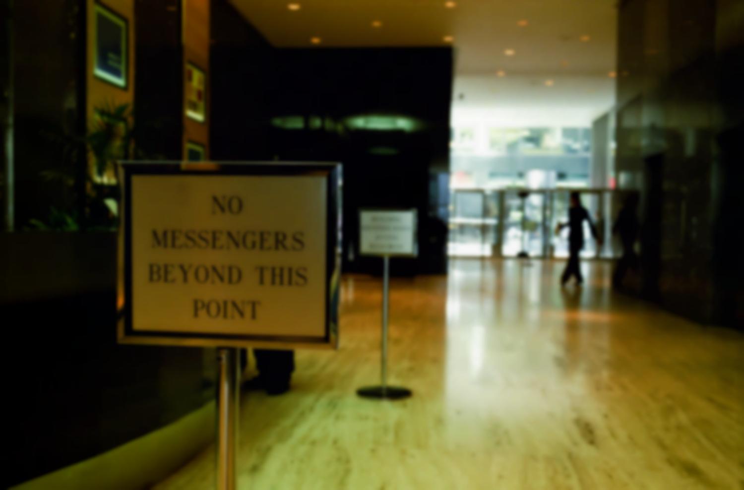 A l'entrée d'un hall d'immeuble dont on aperçoit une autre porte, un panneau interdit le passage : No messengers beyond this point. New York, juillet 2003.