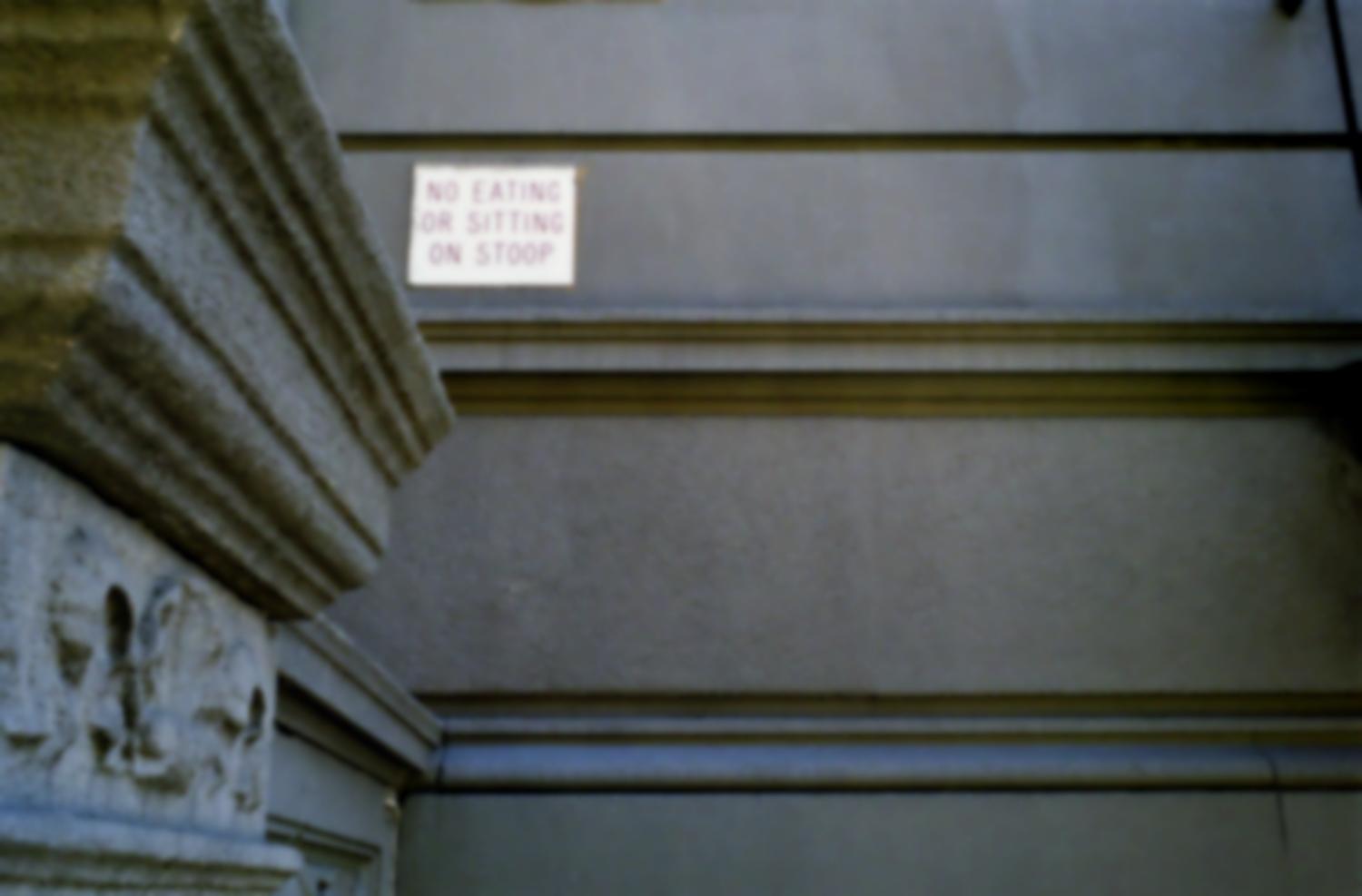 Sur la façade d'immeuble d'habitation, une petite plaque de cuivre : No eating or sitting on stoop. New York, juillet 2003.