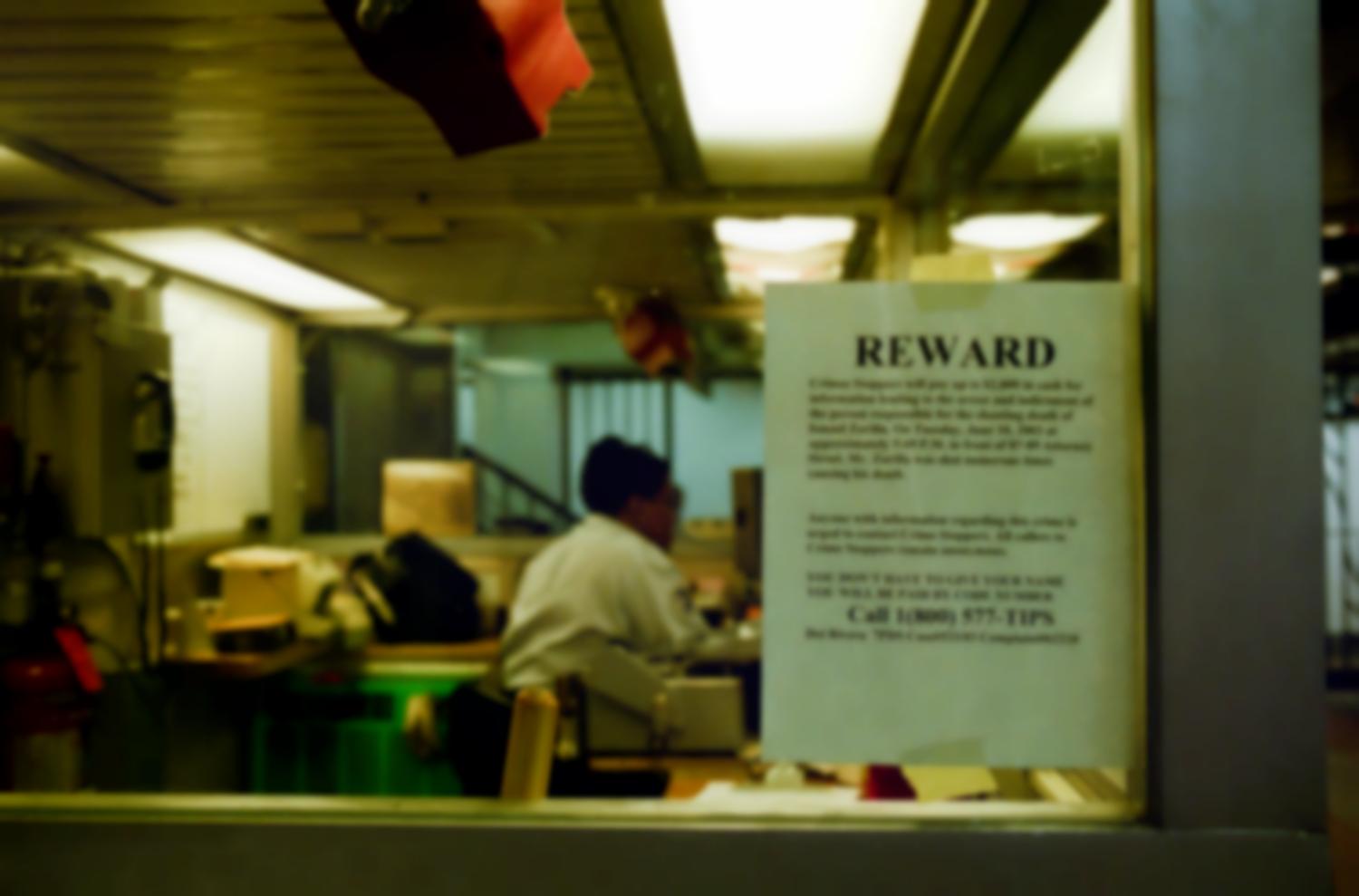Avis de recherche sur la vitre d'un bureau ou d'une loge de concierge : une récompense est proposée par les Crime Stoppers en échange d'informations sur un meurtre. New York, juin 2003.