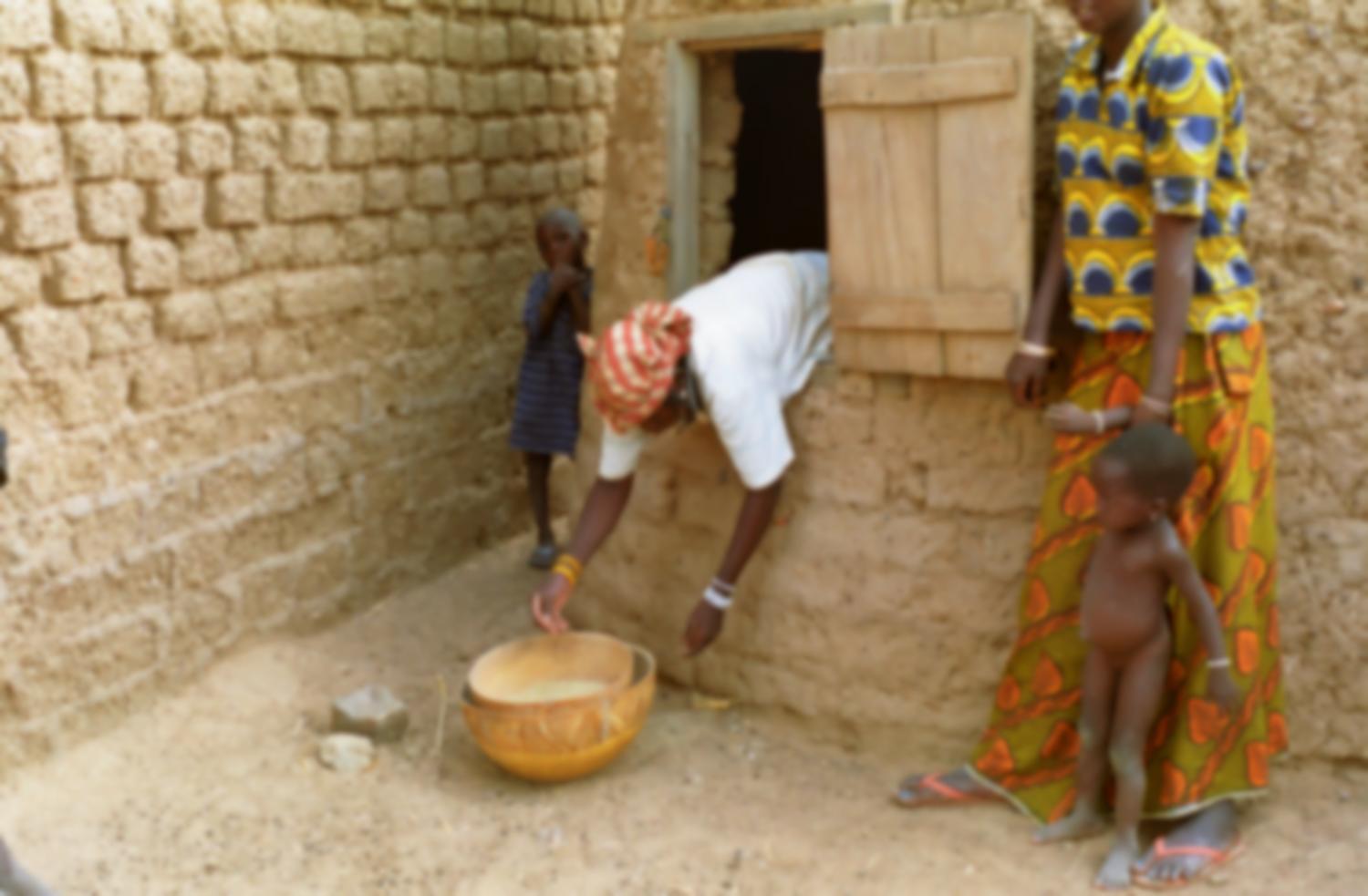 Seul le haut du corps de la belle-fille de Rakia dépasse de l'ouverture du grenier à mil dont elle sort des calebasses de grain. Bosseye Dogabe, Burkina Faso, mai 2008.