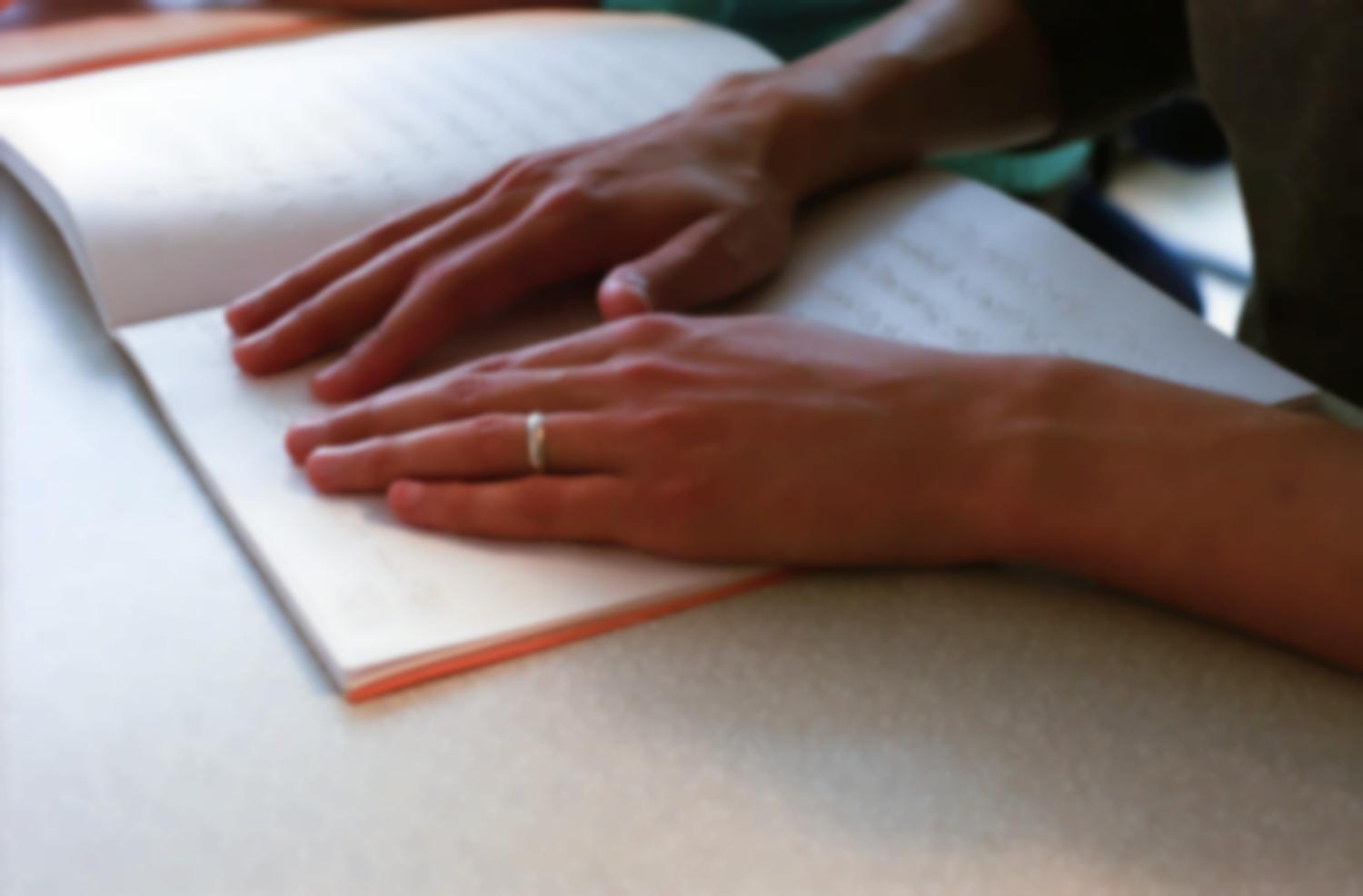 Leçon de braille à l'Association Valentin Haüy : deux mains découvrent le relief d'un livre blanc. Paris, octobre 2005.
