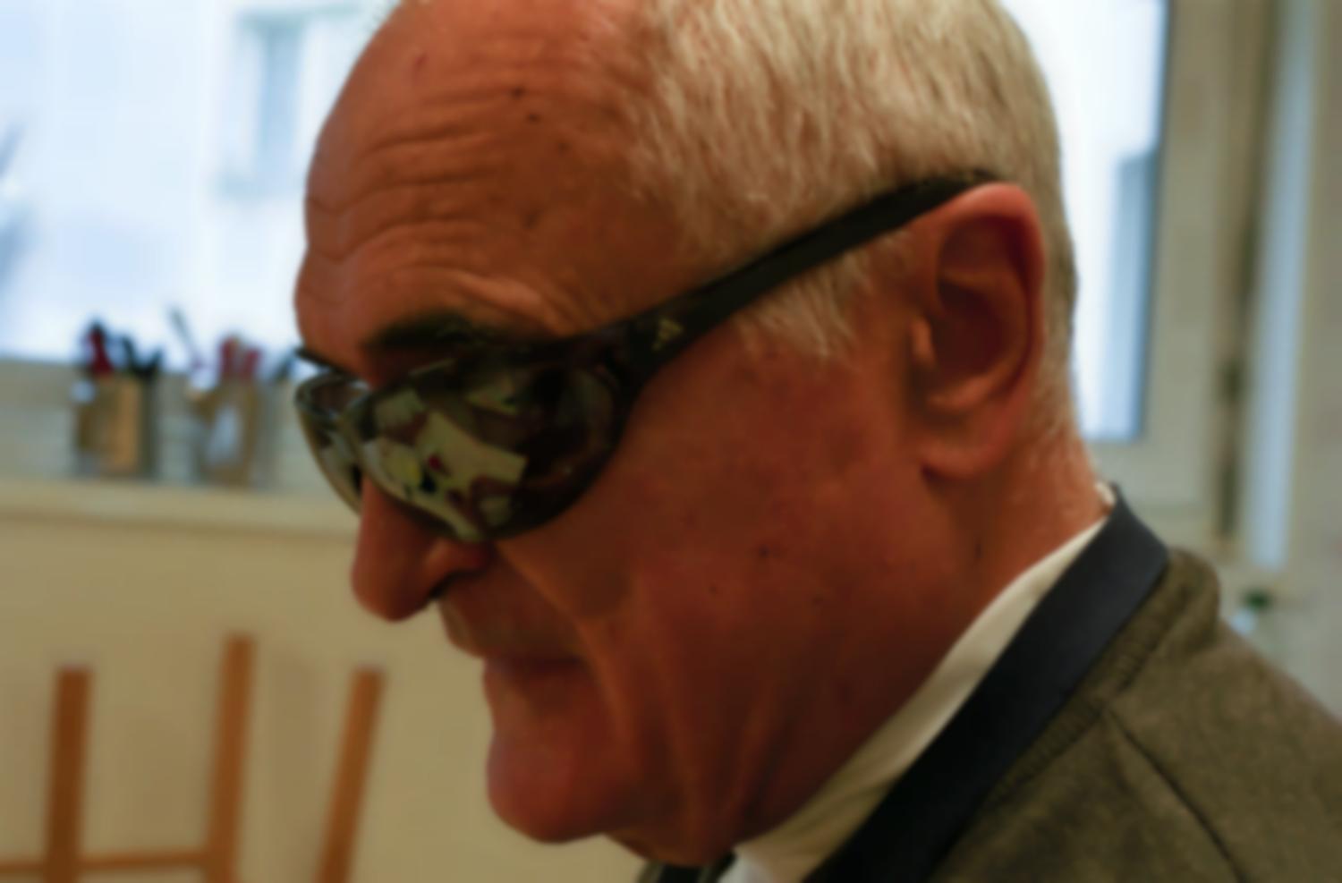 Portrait de Claude au cours d'Autonomie de la vie journalière : dans ses lunettes noires se reflètent ses mains en train d'éplucher de l'ail et les ustensiles qu'il va utiliser pour préparer de l'aïoli . Paris, octobre 2005.