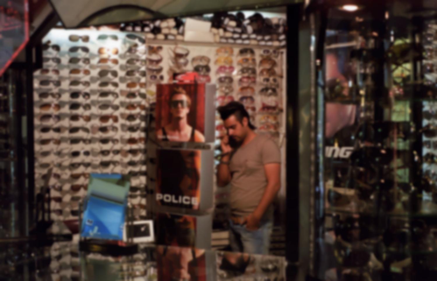 Boutique de lunettes, vendeur en jean, T-shirt, coupe de cheveux à la mode, et publicité avec David Beckham. Iran, septembre 2006.