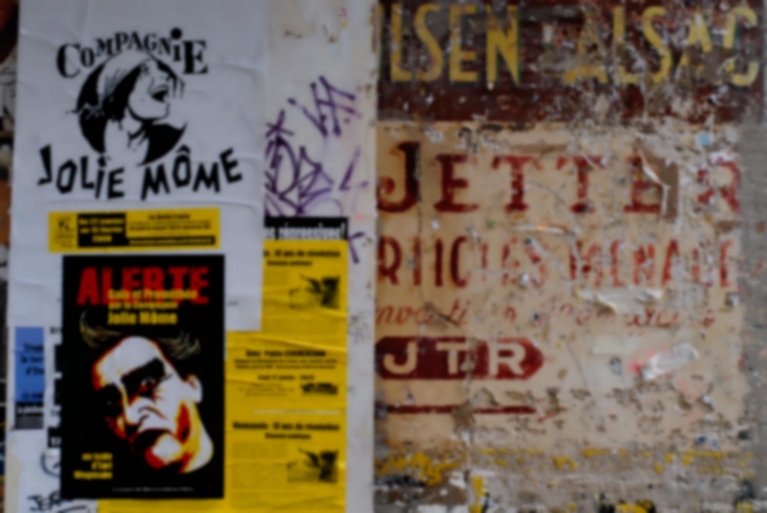 Affiches de la compagnie Jolie Môme et d'une réunion politique sur le Vénézuela, collées sur un mur peint d'une ancienne enseigne cour des Petites Ecuries. Paris, janvier 2009,.