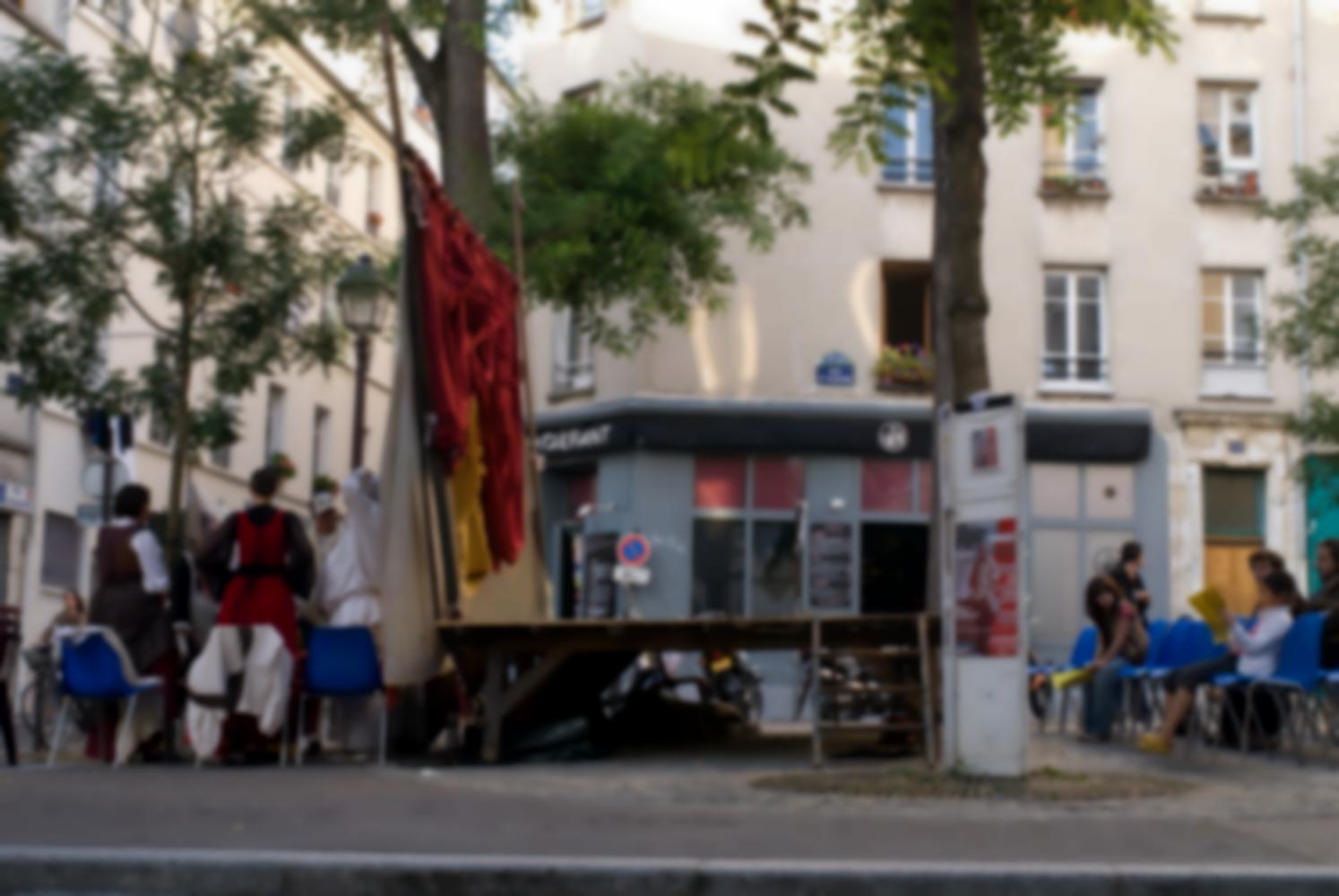 Posés place Sainte-Marthe, des chaises, une scène et des rideaux, derrière lesquels les comédiens se préparent. Paris, août 2010.