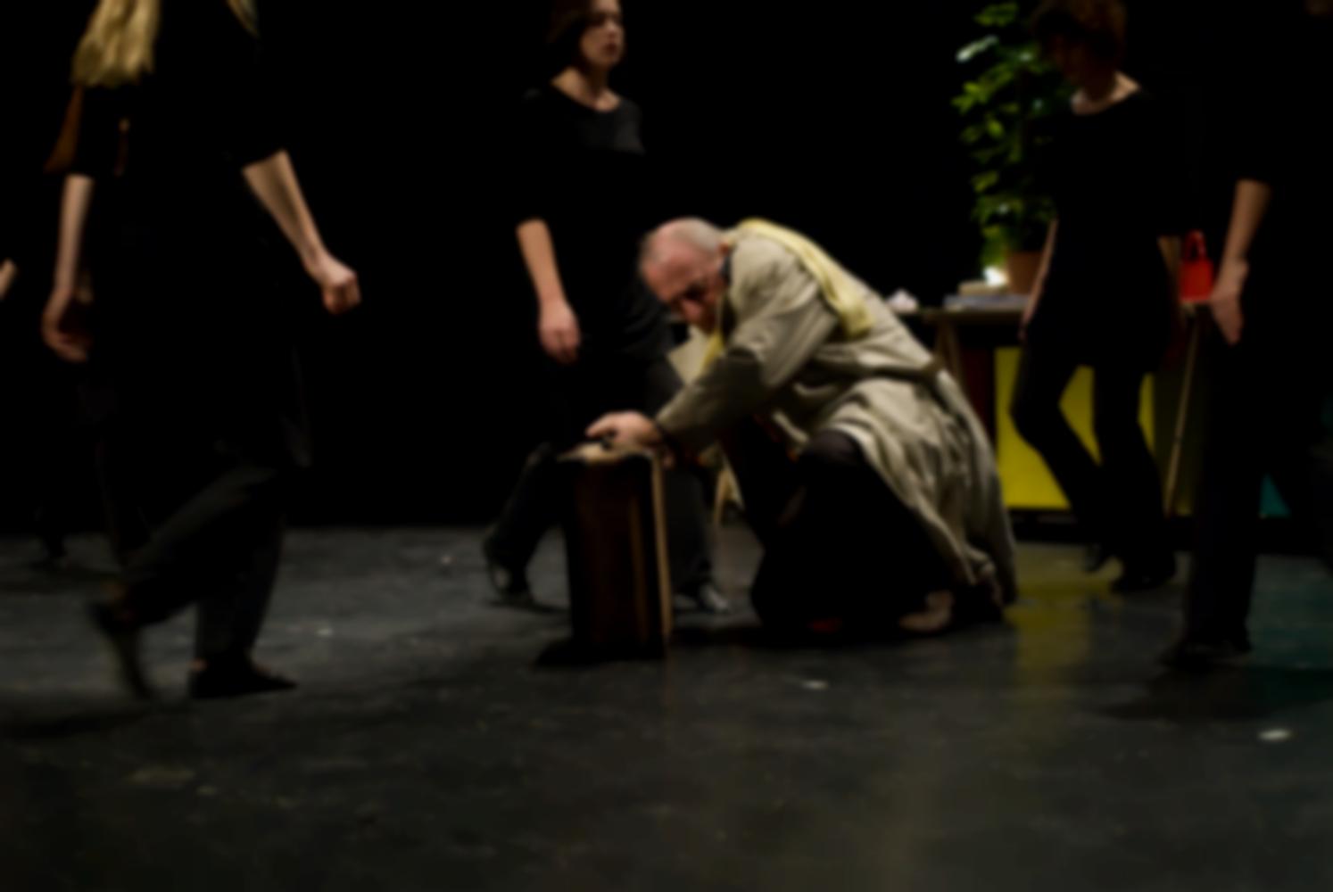 Le chœur se resserre autour du père en imperméable, accroupi près de sa valise dans une position de défense. Nanterre, octobre 2009.
