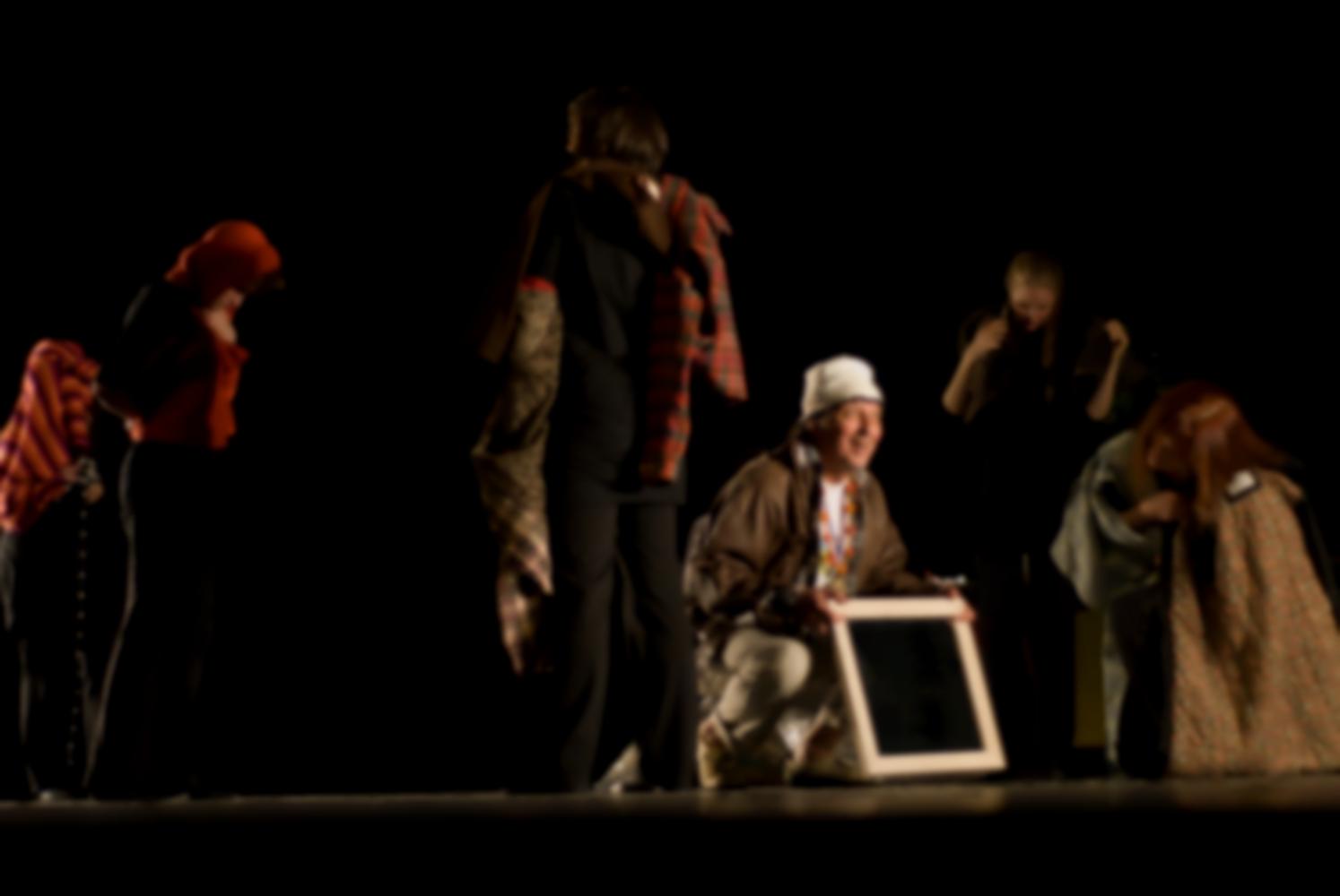 Accroupi parmi les choreutes qui déambulent vêtues de frippes, le clochard, l'air inspiré, tient un miroir. Nanterre, octobre 2009.