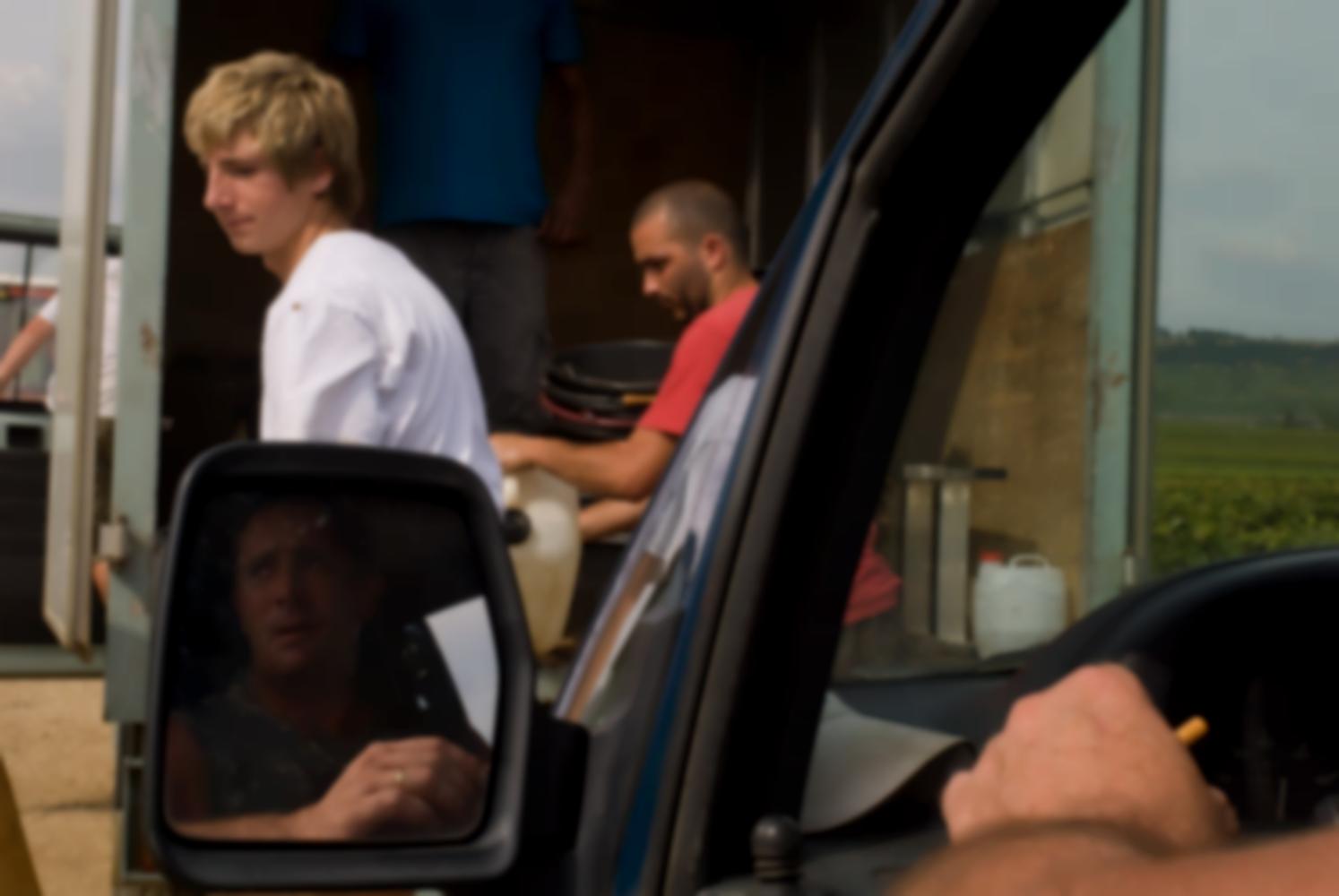 Deux vendangeurs devant le camion, et le reflet d'un troisième dans le rétroviseur de la voiture. Vers Beaune, Bourgogne, septembre 2009.