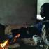Assis devant un feu, Fallou fait griller des grains de café. Touba, Sénégal, février 2008.