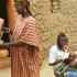 Rakia verse du lait dans une calebasse bouteille, à côté sa belle-fille allaite son enfant. Bosseye Dogabe, Burkina Faso, mai 2008.