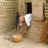 Seul le haut du corps de la belle-fille de Rakia dépasse de l'ouverture du grenier à mil dont elle sort des calebasses de grain. Bosseye Dogabe, Burkina Faso, mai 2008.