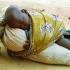 La petite-fille de Rakia fait la sieste, accrochée à un coussin comme au dos de sa mère. Bosseye Dogabe, Burkina Faso, mai 2008.