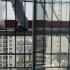 Sur une plateforme de l'échafaudage, la jambe d'un ouvrier à côté d'un sac plastique contenant les paillettes décoratives. Les reflets de la fenêtre cachent sa deuxième jambe. Paris, avril 2010.