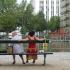 Assises sur un banc, vues de dos, deux femmes regardent le bassin et les barrières métalliques qui les en séparent. Paris, août 2010.