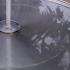 Comme une grande assiette en acier pleine d'eau, la fontaine estampillée Eau de Paris reflète la silhouette d'un arbre et le ciel blanc. Paris, août 2010.