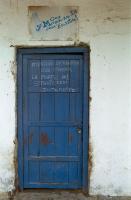 Message sur une porte bleue surmontée d'une publicité Fanta fanée : Attention de rentrer son frapper la porte OK ! Strictement interdite. Obock, Djibouti, mars 2005.