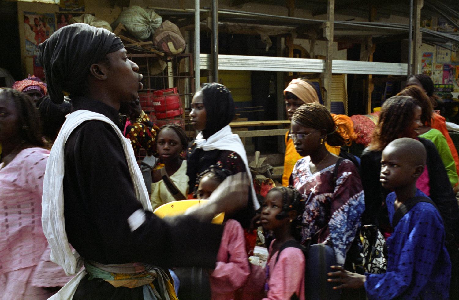 Au milieu d'un flot de passants, Ousmane, un bol à la main, appelle, chante, mendie. Touba, Sénégal, février 2008.