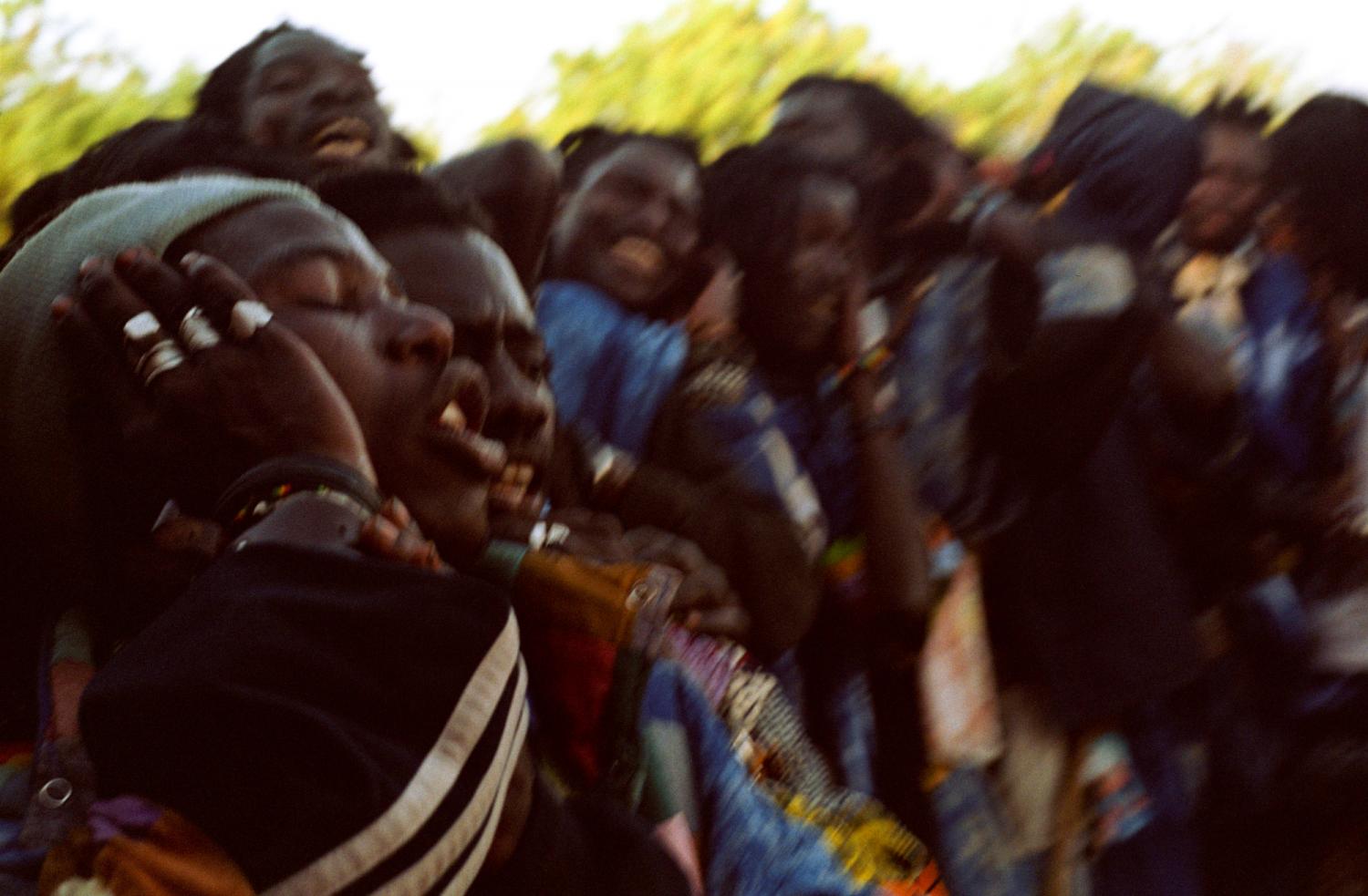 Les mains aux oreilles, les Baye Fall en file forment un cercle, tournent et chantent en invoquant le nom de Dieu. Touba, Sénégal, février 2008.