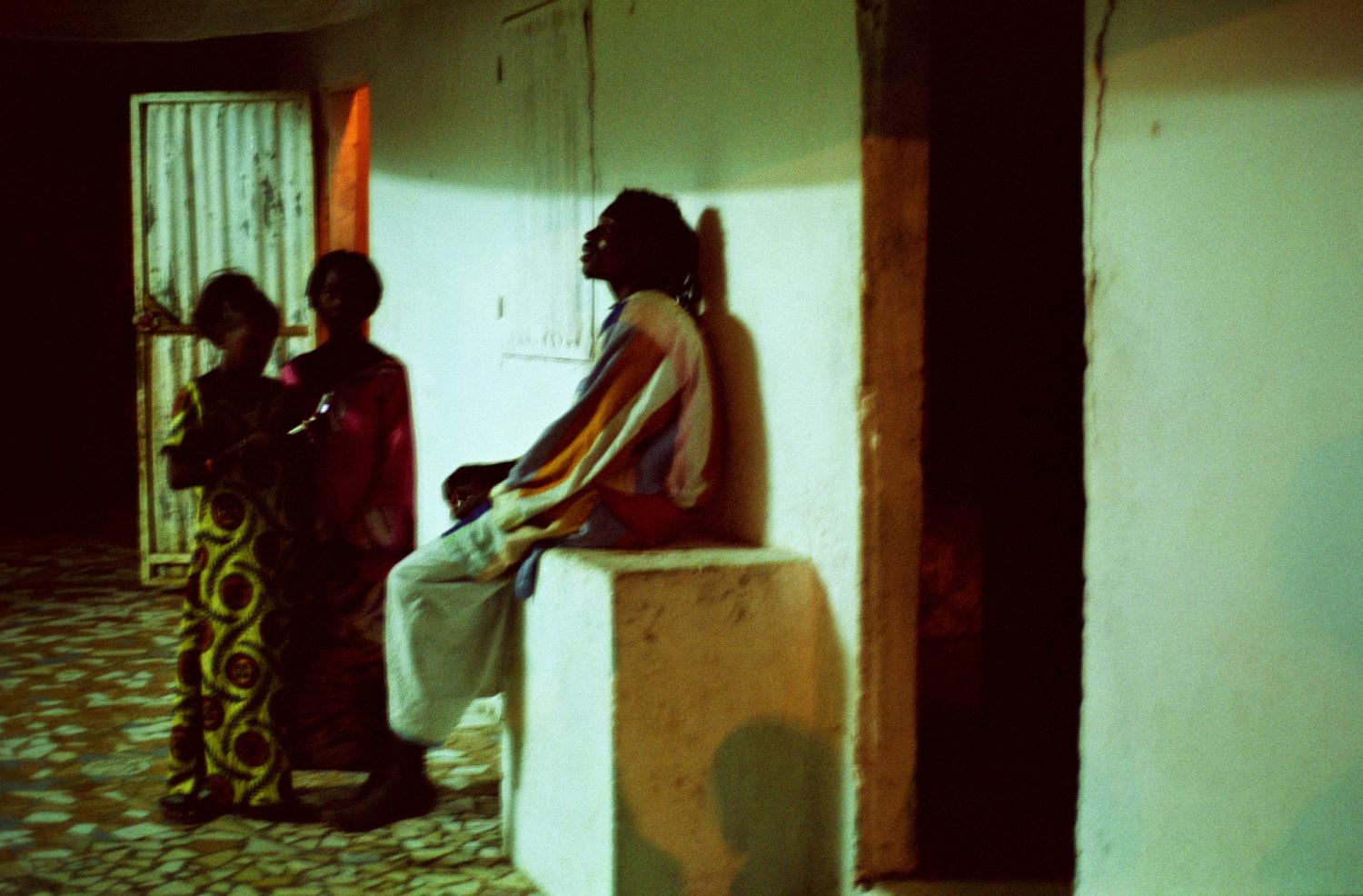 Dans la cour d'une maison pendant les nuits de fête, un Baye Fall discute avec deux jeunes filles. Touba, Sénégal, février 2008.