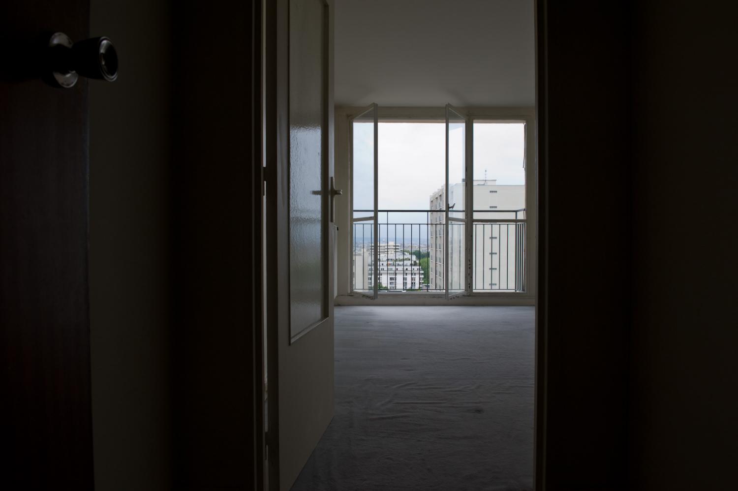 Mon appartement vide avant l'état des lieux : une porte vitrée ouverte, une grande pièce avec de la moquette, la baie vitrée, le balcon, la vue. Paris, août 2011.