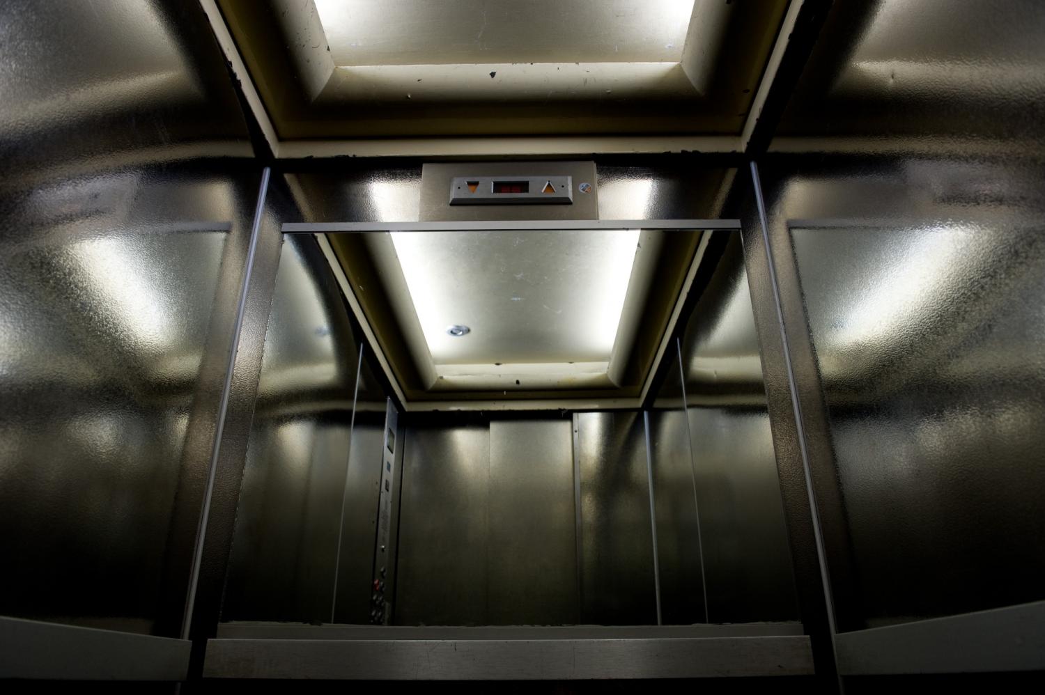Le grand ascenseur  se reflète dans son miroir avec ses parois chromées et ses néons. Paris, août 2011.