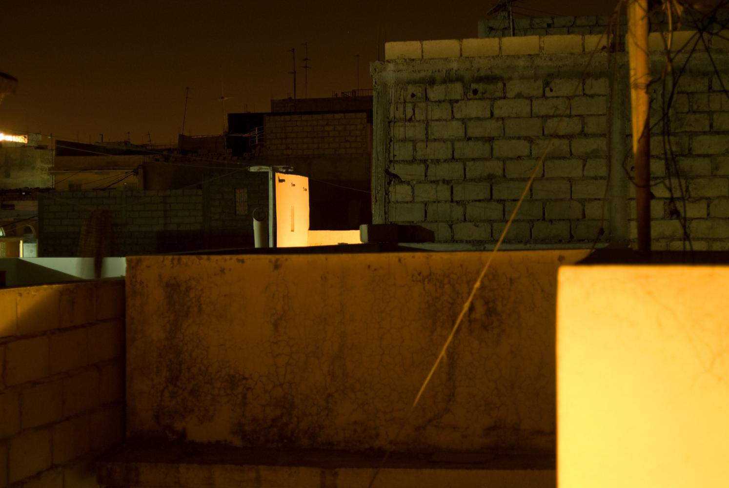 Les immeubles voisins de nuit, murs de parpaings ou peints, parfois éclairés par une lumière orange. Dakar, Sénégal, mars 2010.
