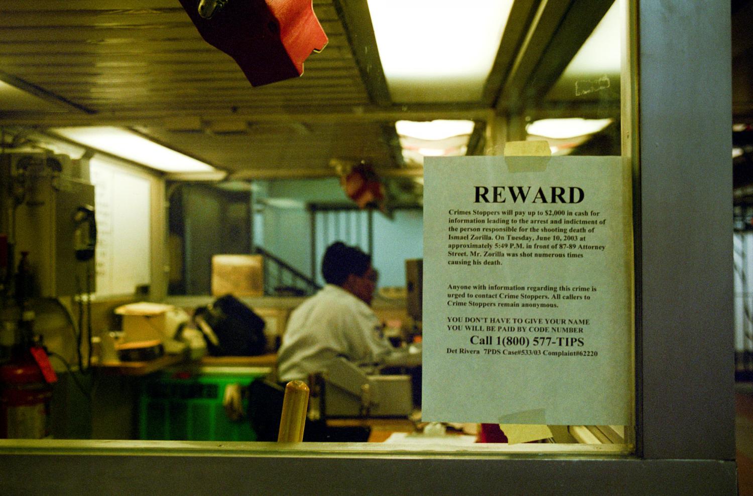 Avis de recherche sur la vitre d'un bureau ou d'une loge de concierge : une récompense est proposée par les Crime Stoppers en échange d'informations sur un meurtre. New York, juin 2003.