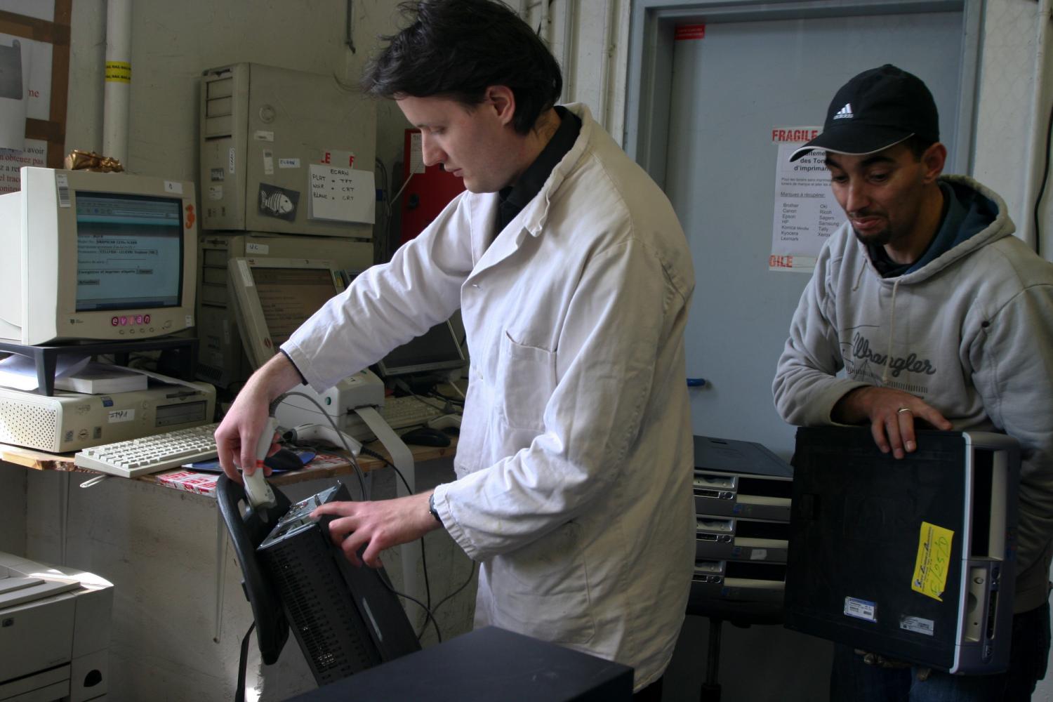 A l'entrée en stock, Vincent et Salim posent des codes barre sur les ordinateurs. Paris, avril 2009.