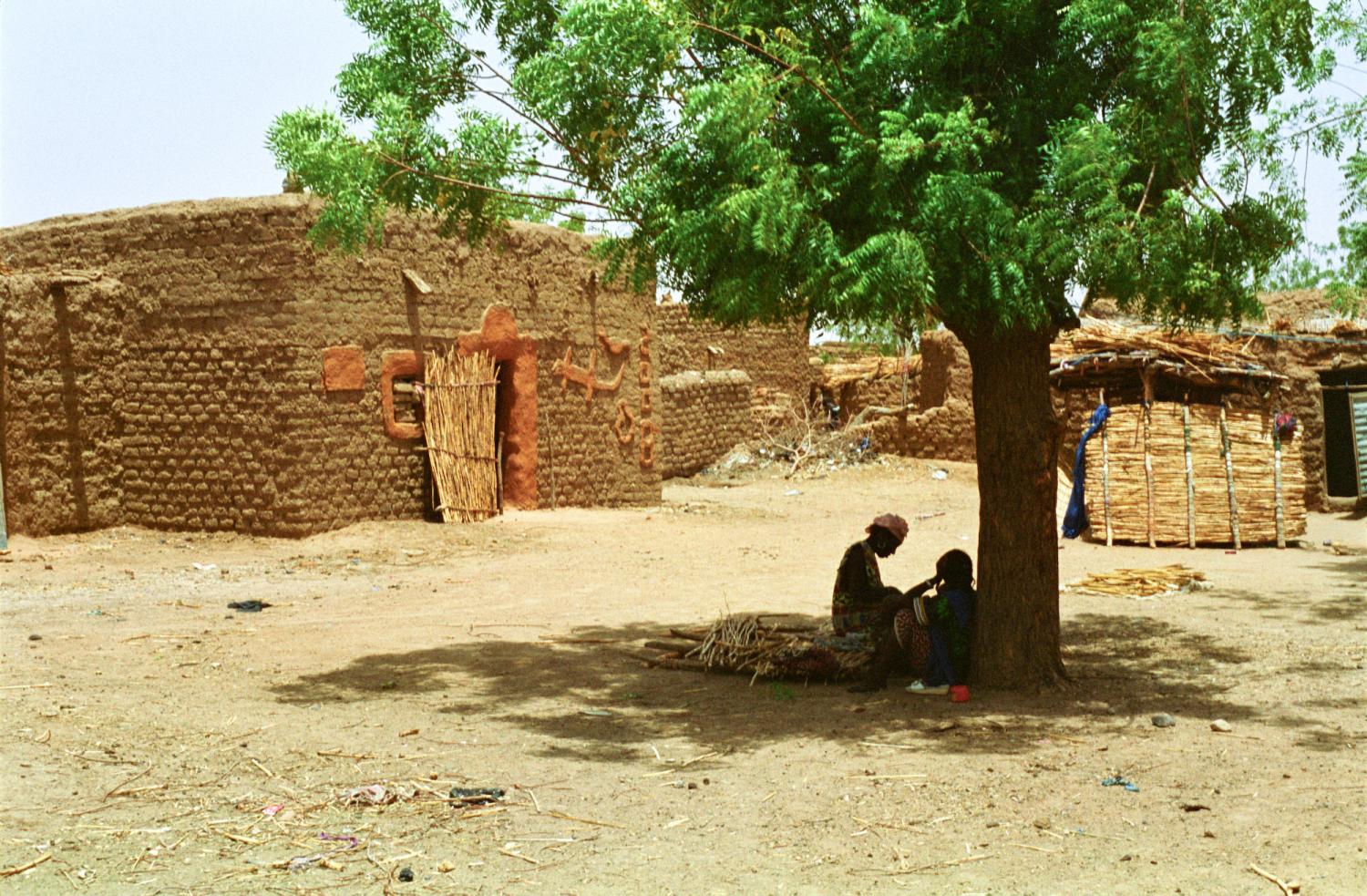 Deux femmes à l'ombre d'un arbre, devant une maison de banco décorée de dessins en relief. Bosseye Dogabe, Burkina Faso, mai 2008.