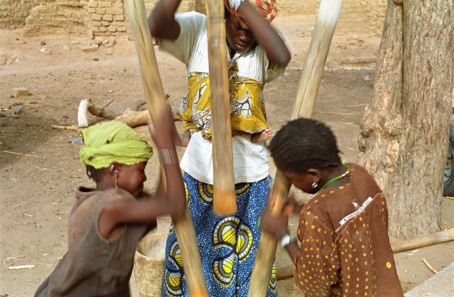 Son bébé dans le dos, la belle-fille de Rakia pile en cadence avec deux de ses nièces. Bosseye Dogabe, Burkina Faso, mai 2008.