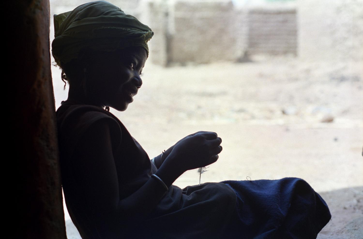 Assise dans l'encadrement d'une porte, une petite-fille de Rakia à contrejour. Bosseye Dogabe, Burkina Faso, mai 2008.