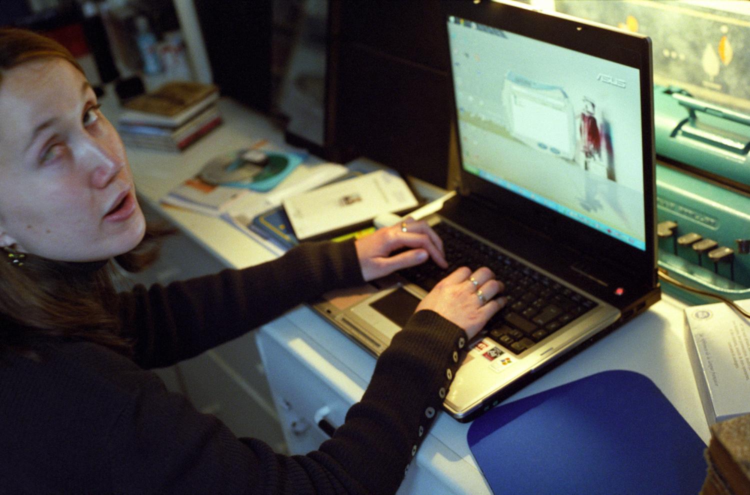 Céline devant son ordinateur portable équipé d'un logiciel de synthèse vocale. Derrière se cache une machine à écrire en braille Perkins, délaissée. Paris, janvier 2006.