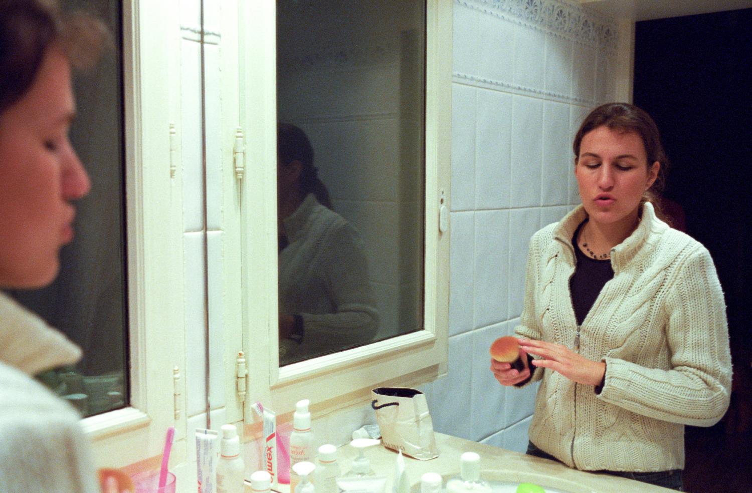Laetitia se maquille devant le miroir de sa salle de bains. Paris, mars 2006.
