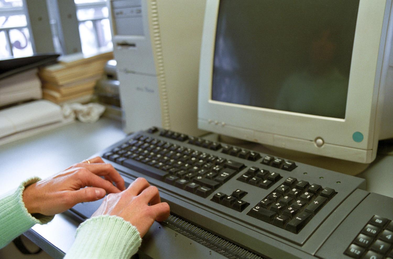 A l'imprimerie de l'Association Valentin Haüy, deux mains sur une plage braille, un écran d'ordinateur éteint : Valérie relit des documents. Paris, novembre 2005.