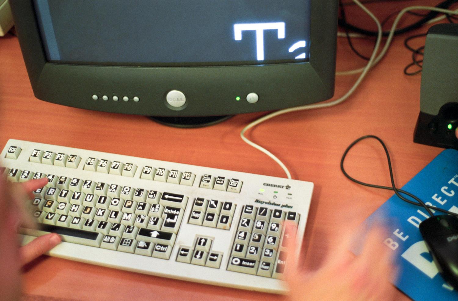 Un écran où l'on aperçoit une très grande lettre blanche sur fond noir, un clavier où les lettres sont écrites en gras sur les touches, et les mains d'un utilisateur : c'est un ordinateur adapté pour les malvoyants. Paris, octobre 2005.