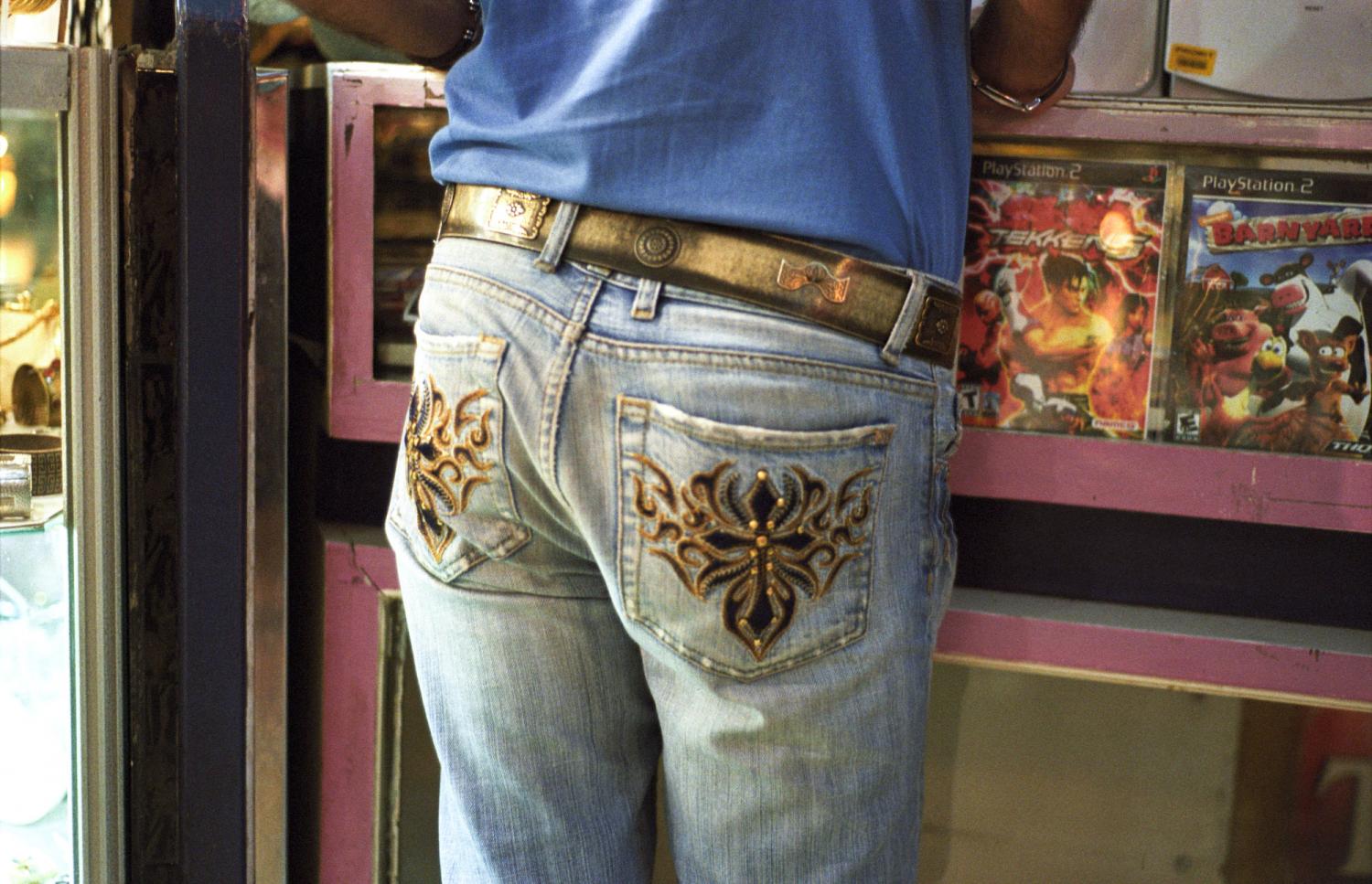 Au comptoir d'une boutique de DVD, gros plan sur les poches arrière, ornées de broderies, d'un jean. Téhéran, Iran, septembre 2006.