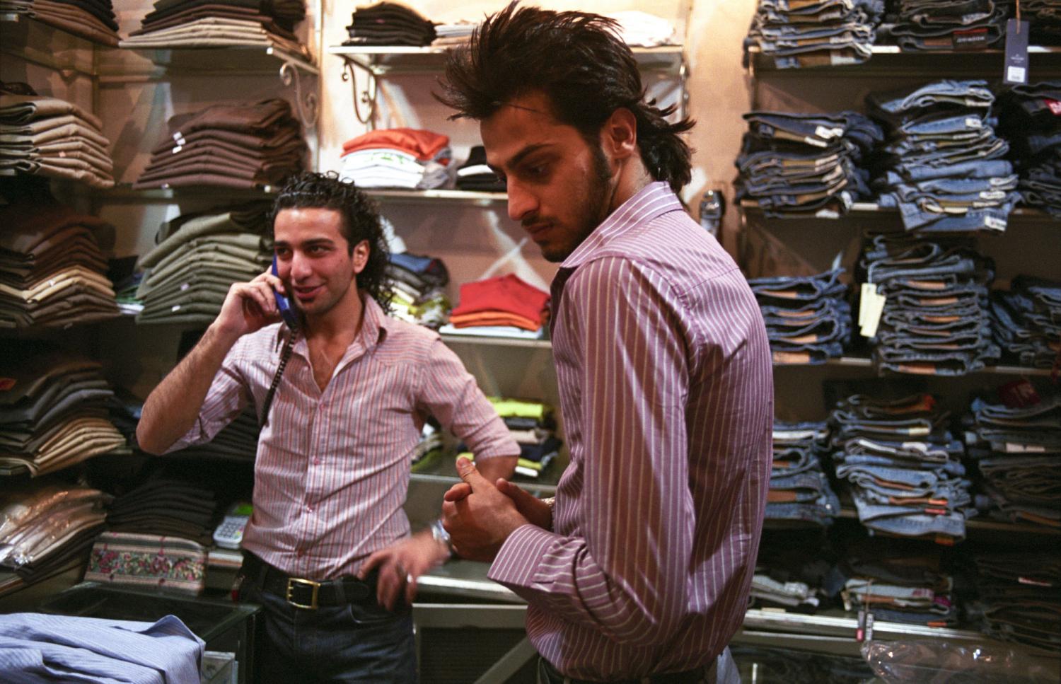 Un vendeur et son ami, tous deux en chemises à rayures, dans une boutique de jeans d'un centre commercial du nord de Téhéran. Iran, septembre 2006.