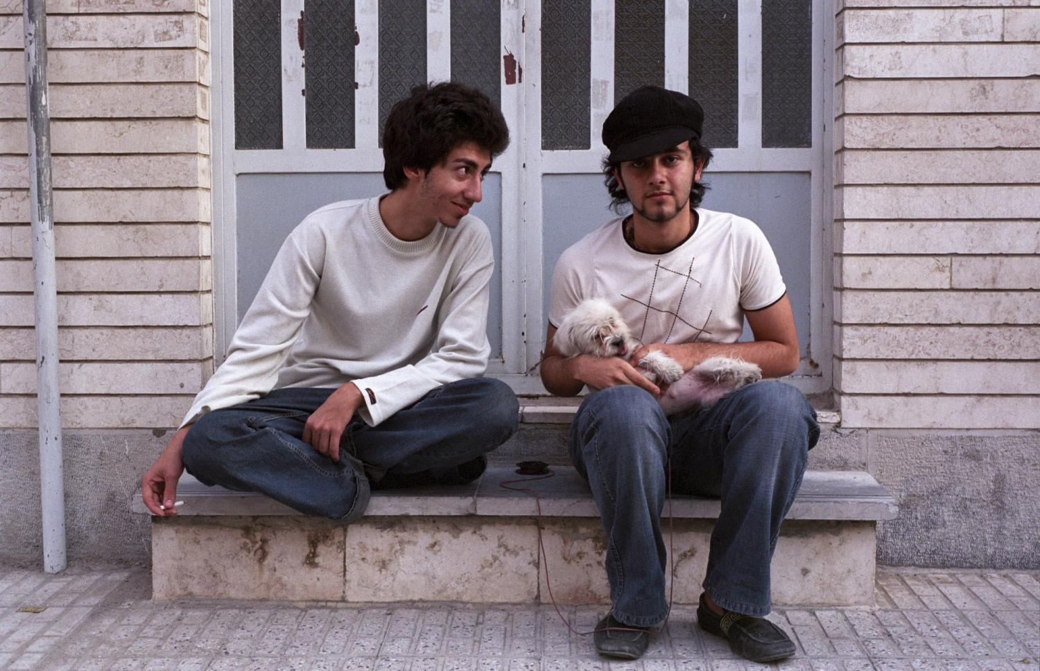 Deux jeunes gens et un petit chien sur le perron d'un immeuble de quartier résidentiel. Téhéran, Iran, octobre 2006.