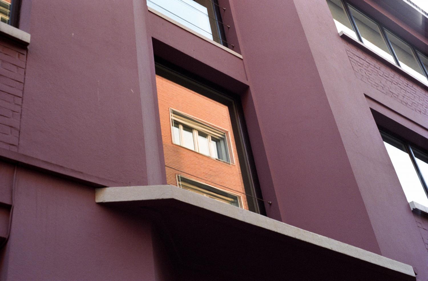 Façade d'un immeuble mauve, et dans une de ses fenêtres, reflet d'un autre en briques. Paris, printemps 2006.