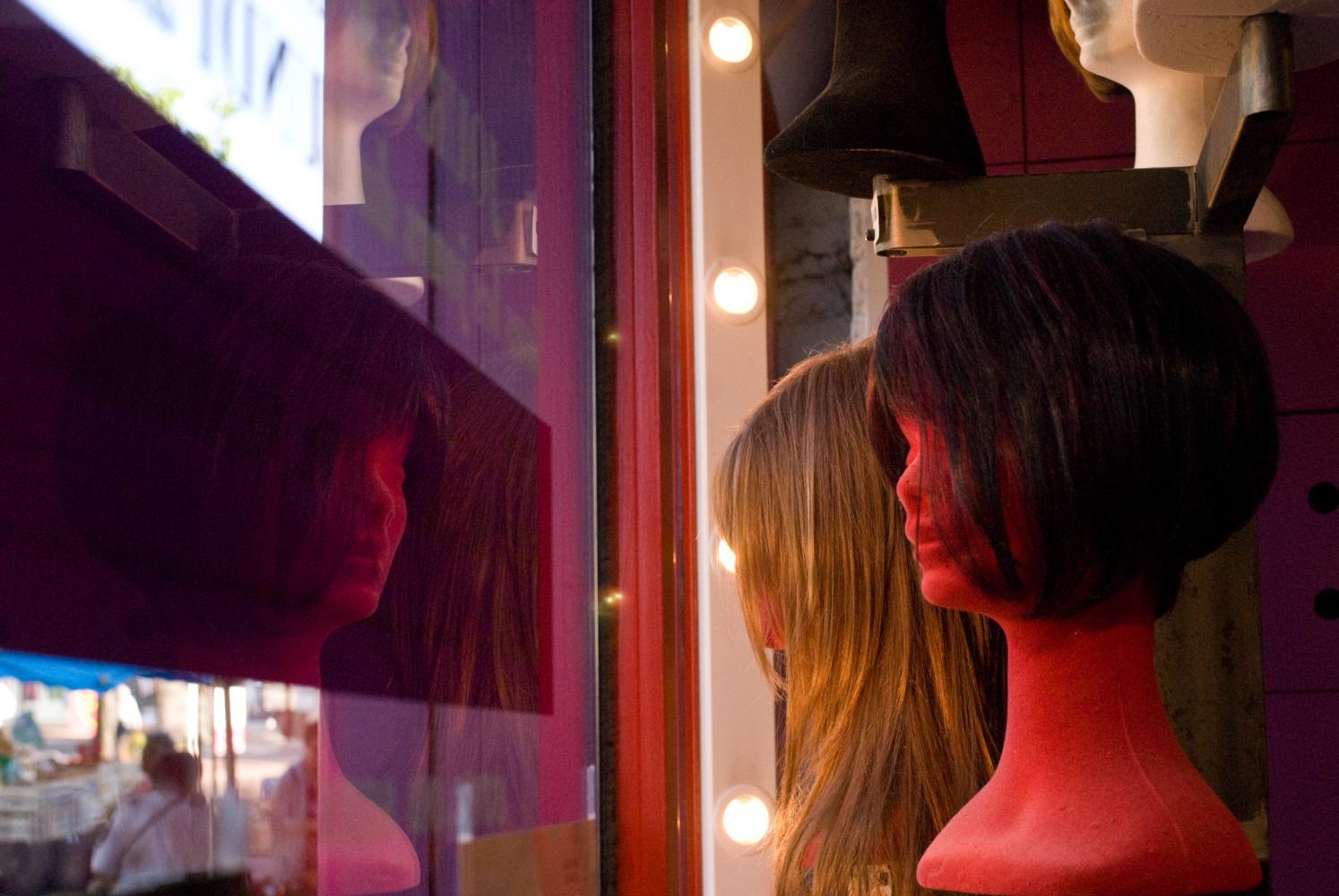 Présentoirs de perruques dans la vitrine d'un coiffeur. Vierzon, août 2009.