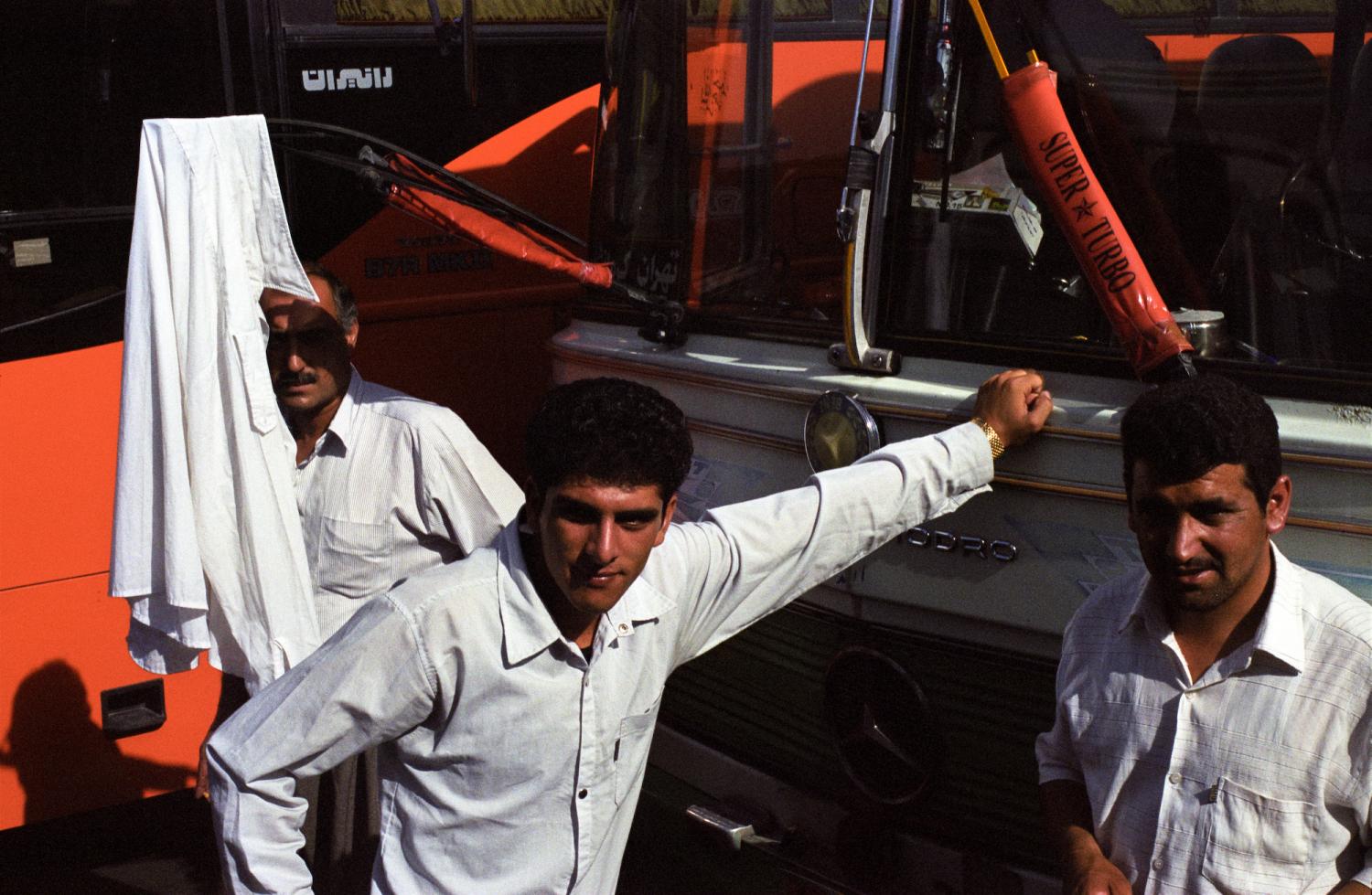 A la gare routière, trois hommes parmi les bus, une chemise blanche accrochée à un essuie-glace. Téhéran, Iran, juillet 2006.