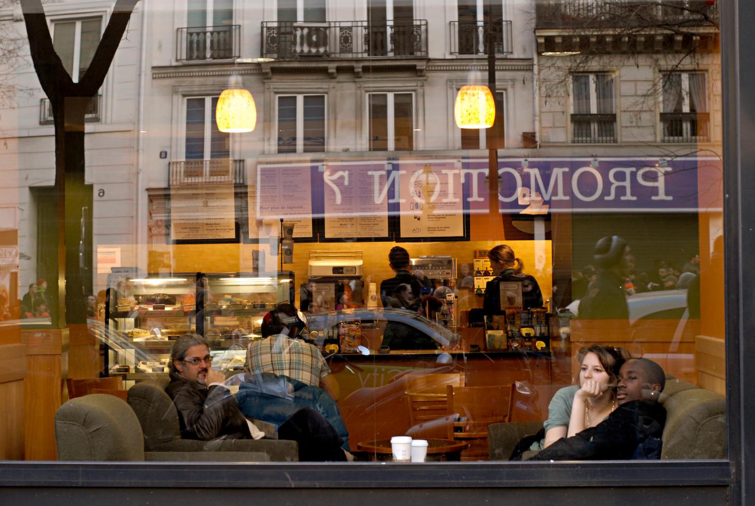 Derrière la vitrine d'un café des grands boulevards, des clients regardent passer une manifestation. Paris, janvier 2009.