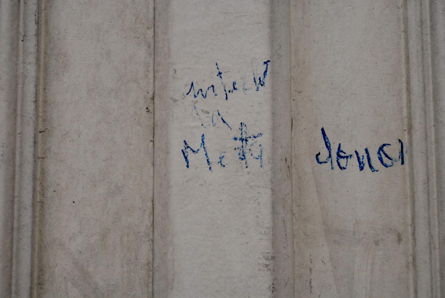 Quelques mots illisibles écrits au pastel bleu sur une porte du Faubourg Saint-Denis. Paris, février 2009.