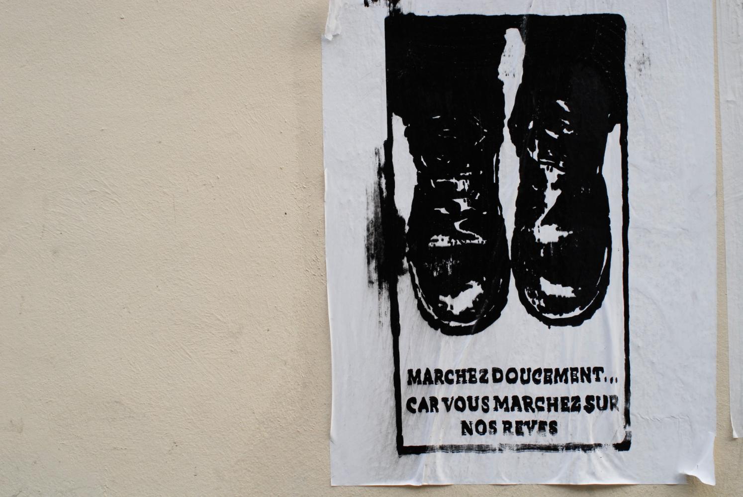 Graffiti au pochoir réalisé sur une affiche blanche, représentant des pieds chaussés de godillots au-dessus de quelques lignes. Paris, avril 2009.