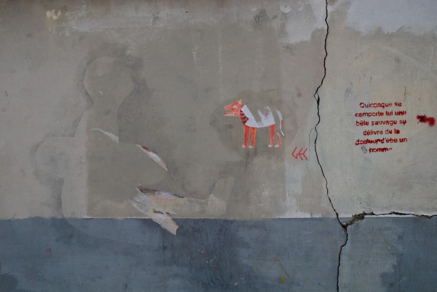 Collage déchiré représentant un animal orange, silhouette d'un autre collage, et de l'autre côté d'une lézarde, une phrase au pochoir. Paris, mai 2010.