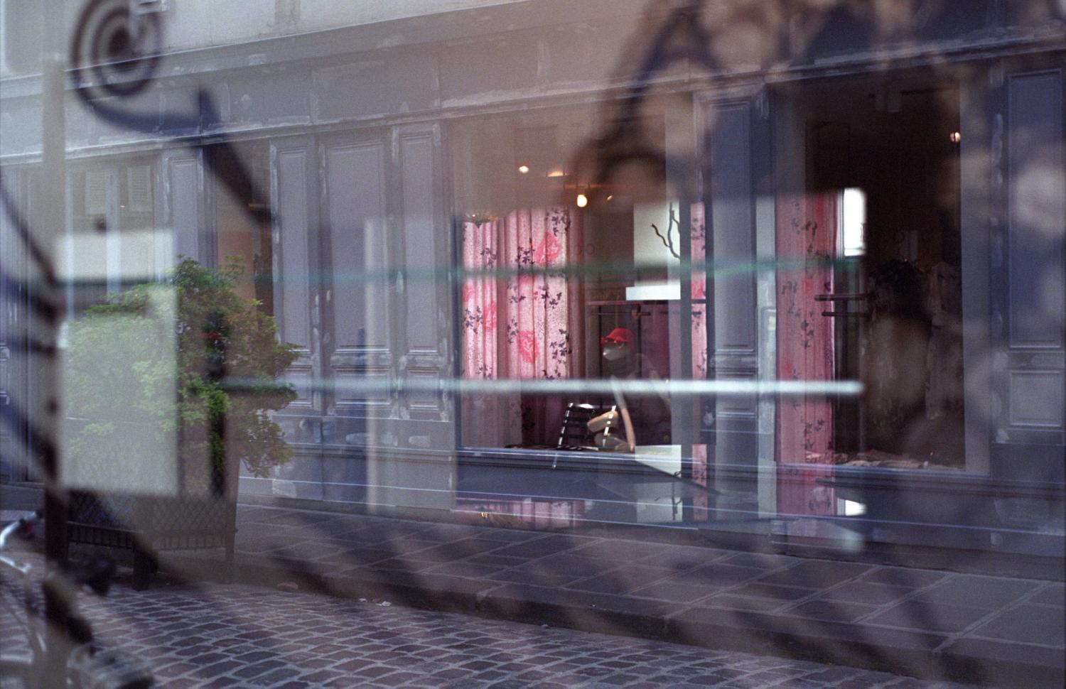 Reflets d'une vitrine aux rideaux roses. Paris, juillet 2007.