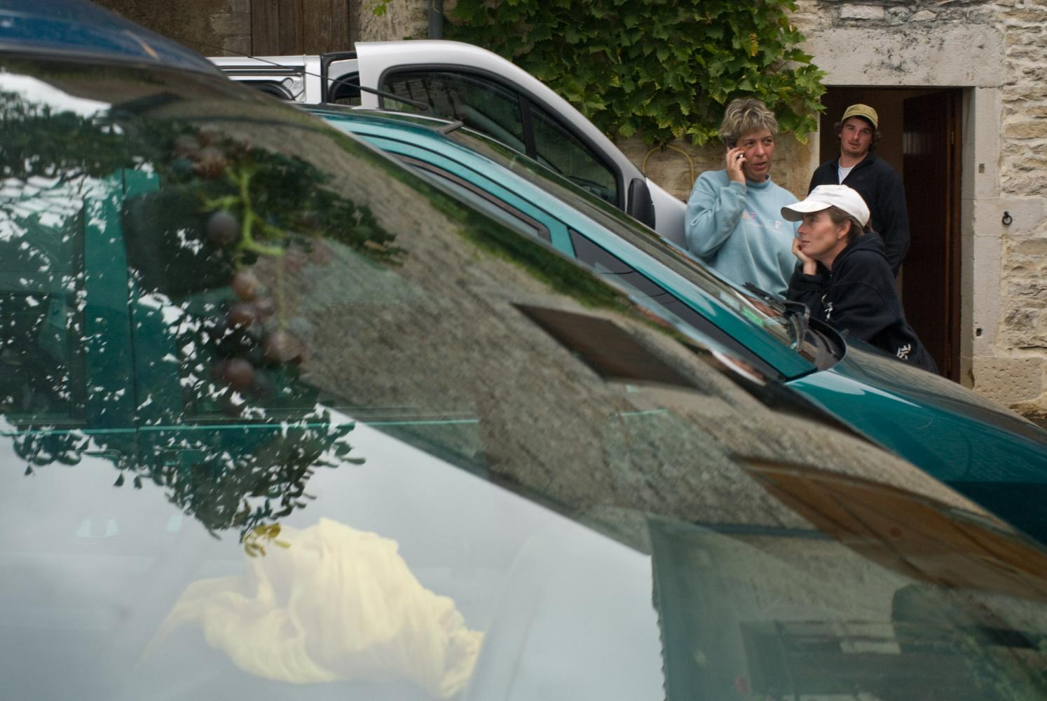 Perdus parmi les voitures, des vendangeurs attendent de repartir au travail après la pause déjeuner. Chassagne-Montrachet, Bourgogne, septembre 2009.